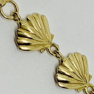 May include: Gold chain bracelet with a seashell design. The chain is made of small, linked circles and each seashell is detailed with ridges.