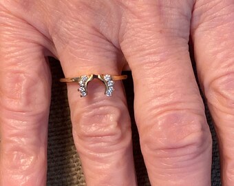 May include: A gold ring with a horseshoe design and small clear stones.