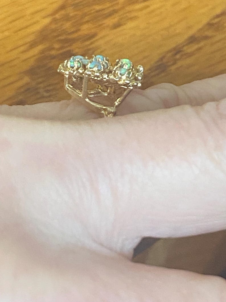 Op de afbeelding: Een gouden ring met drie opalen gezet in een bloemmotief.