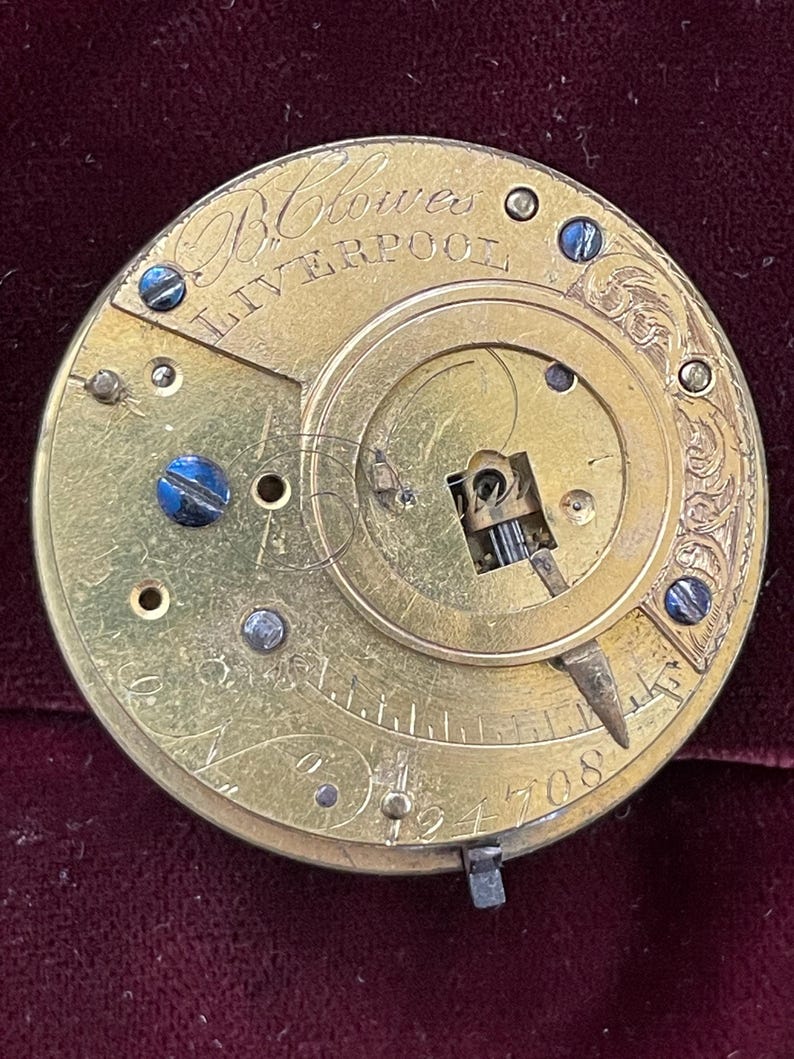 Op de afbeelding: Close-up van een goudkleurig zakhorlogemechanisme met de inscriptie "Blowes Liverpool" en het nummer "194708".