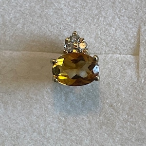 May include: A gold ring with a large oval-shaped topaz gemstone and a cluster of smaller diamonds set in the center.