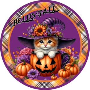 May include: A round, fall-themed graphic features a cute orange tabby kitten wearing a witch hat and sitting in a jack-o'-lantern. The design includes pumpkins, flowers, and the text "HELLO FALL" in a decorative font. The border has a plaid pattern.