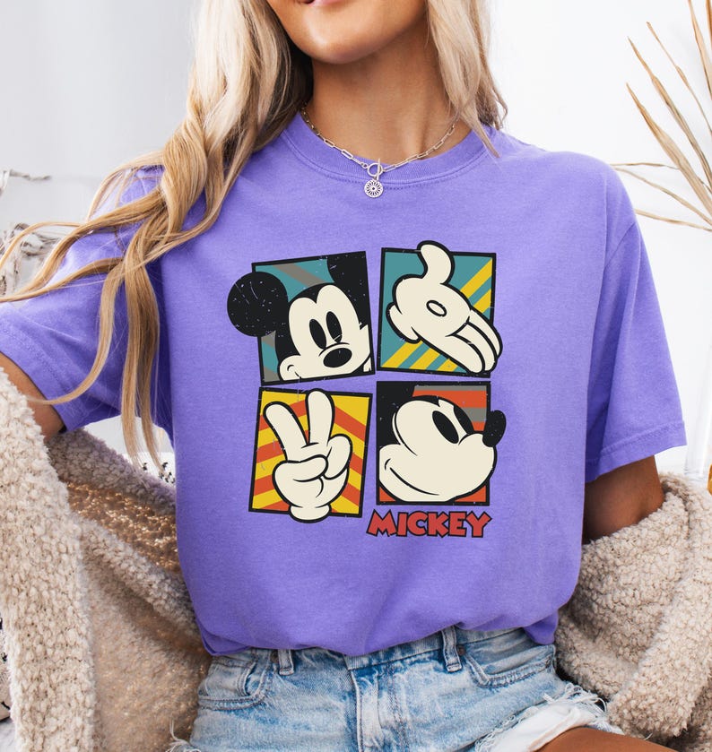 May include: Purple short-sleeved t-shirt with a vintage-style graphic of Mickey Mouse in four different poses. The graphic includes the text "MICKEY".