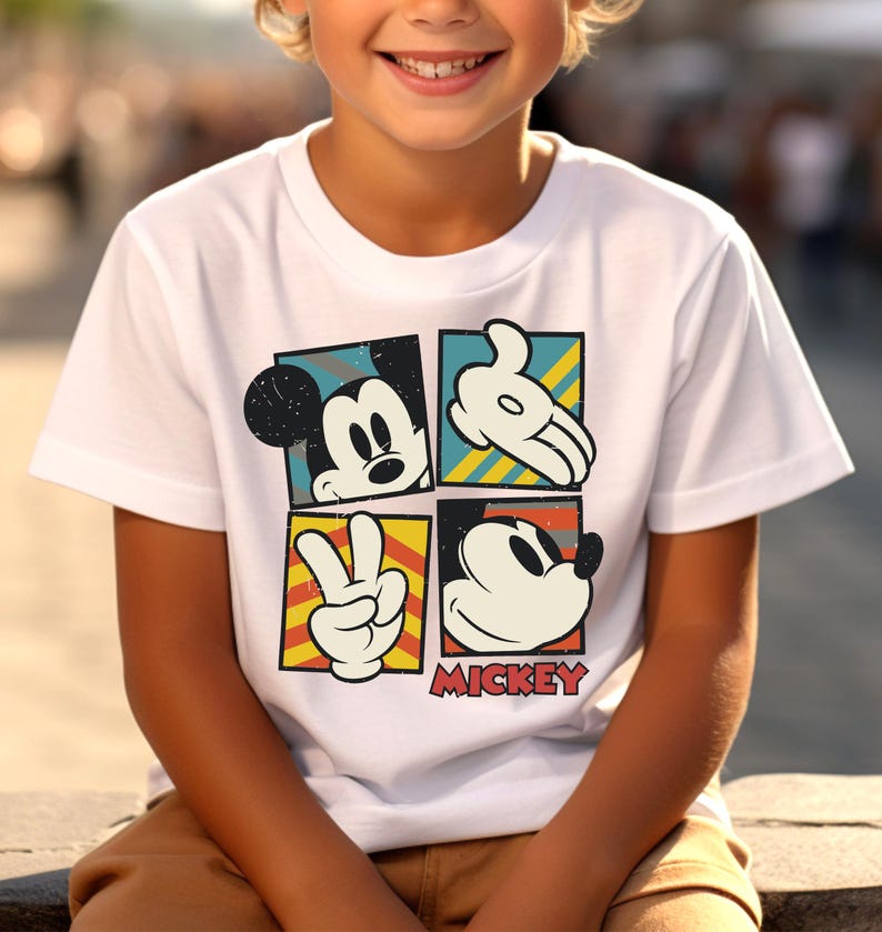 May include: White t-shirt with a colorful graphic of Mickey Mouse in four different poses. The graphic includes the text "MICKEY".