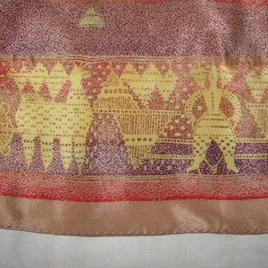 Peut inclure: Gros plan sur un tissu avec un motif répété de figures stylisées en or sur fond violet. Le tissu a une bordure rouge et or.