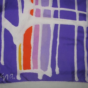 May include: A square scarf featuring a deep purple background with a large, white, abstract, grid-like pattern. The design includes vertical stripes in yellow, orange, pink, and light purple. The word "Vera" is printed in white in the bottom left corner.