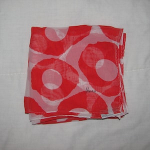 May include: A red and white patterned scarf with a white circle design. The scarf is made of a sheer fabric and has a brand label that says "Usma".