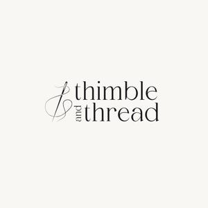Puede incluir: Un logotipo con las palabras "thimble and thread" en una fuente serif. Una aguja e hilo se representan en un estilo minimalista, colocados a la izquierda del texto. El fondo es de color neutro.