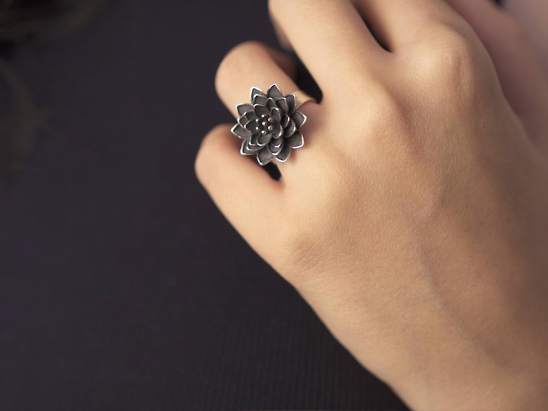 Puede incluir: Un anillo de plata con un dise&ntilde;o de flor negra.