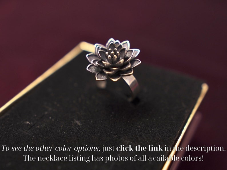 Puede incluir: Un anillo de plata con un dise&ntilde;o de flor de loto negra. El centro de la flor es de oro.