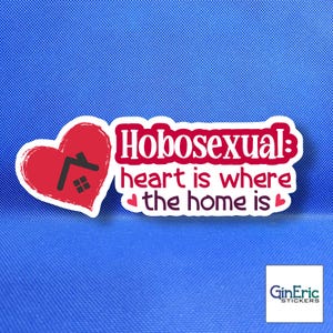 May include: A die-cut sticker featuring a red heart with a black house icon inside. The text reads "Hobosexual: heart is where the home is" in dark red and purple lettering, accented with two small pink hearts on a white background border.