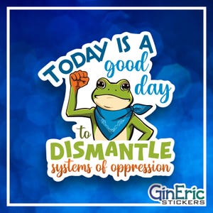 May include: A sticker featuring a cartoon frog with a blue bandana and raised fist. The sticker has the text "TODAY IS A good day to DISMANTLE systems of oppression" in white and green. The background is blue.