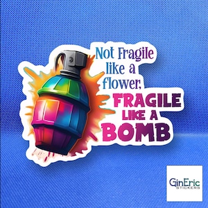 May include: A sticker featuring a colorful cartoon grenade with the text "Not Fragile like a flower, FRAGILE LIKE A BOMB." The grenade is a mix of pink, blue, green, and orange. The sticker has a white border and a blue background.