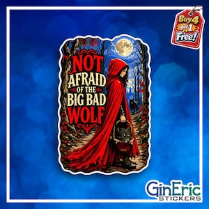 May include: A rectangular sticker featuring a person in a red hooded cloak walking through a dark forest under a full moon. The text reads NOT AFRAID OF THE BIG BAD WOLF. The person carries a basket containing a wolf head in the foreground.