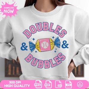 May include: White sweatshirt with a pink and blue graphic design that says "DOUBLES & BUBBLES" with a baseball inside a candy. The graphic is surrounded by stars.