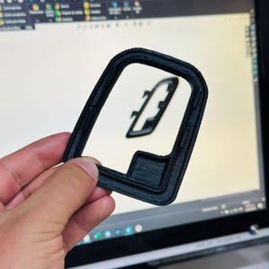Op de afbeelding: Een zwart plastic 3D-geprint frame met een rechthoekige vorm en een kleinere rechthoekige uitsparing in het midden.