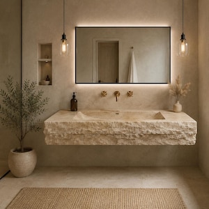 May include: A wall-mounted bathroom vanity featuring a rectangular, rough-hewn natural stone sink basin. The unit includes a large, rectangular, backlit mirror, gold-toned wall-mounted taps, and two glass pendant lights hanging above the stone counter.