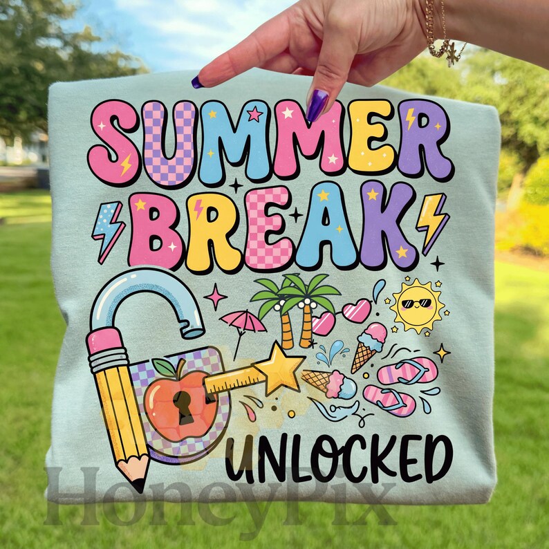 May include: A pale blue t-shirt featuring the text "SUMMER BREAK UNLOCKED" in vibrant, bubble-style lettering. The design incorporates summer-themed illustrations such as palm trees, ice cream, and flip-flops.