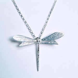 bright silver dragonfly necklace on a white background