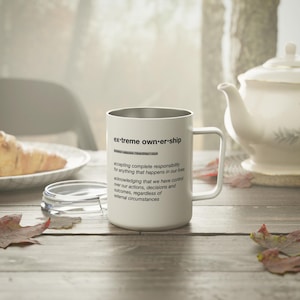 May include: White stainless steel travel mug with a black inscription that reads "ex-treme own-er-ship" and a definition of the term.