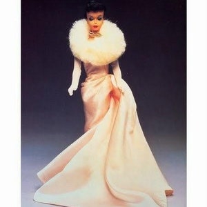 May include: A vintage Barbie doll wearing a white fur stole and a long, flowing pink gown. The doll is posed with her hands on her hips and her head tilted slightly to the side. The image is titled "APF # 050 Enchanted Evening".