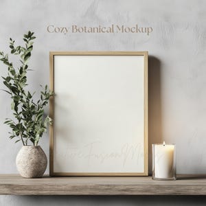 May include: A wooden frame with a white background sits on a wooden shelf. A small potted plant and a lit candle are on the shelf next to the frame. The text "Cozy Botanical Mockup" is at the top of the image.