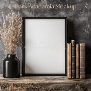 Puede incluir: Una maqueta enmarcada en negro con el texto "Dark Academia Mockup" y un espacio en blanco para una impresión. Un jarrón negro con plantas secas y una pila de libros antiguos están sobre una superficie de madera.