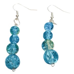 May include: Two dangling earrings with a silver hook and a series of blue, crackled glass beads. The beads vary in size and shade, creating a textured and layered effect. The earrings are displayed against a white background.