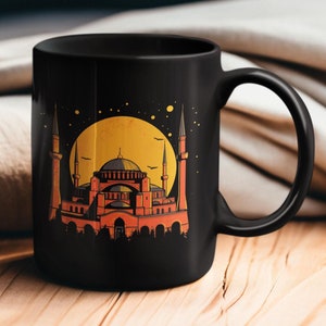 May include: Black ceramic mug with a graphic of a mosque in front of a yellow moon and a dark blue night sky.