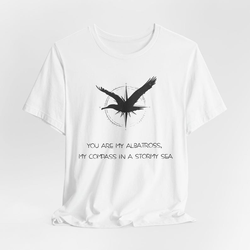 May include: White t-shirt with a black albatross graphic and compass design. The text "You are my albatross, my compass in a stormy sea" is printed below the graphic.