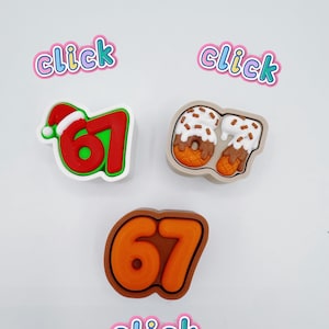 Könnte beinhalten: Drei farbenfrohe Charms mit der Zahl 67. Einer ist rot mit Weihnachtsmütze, ein weiterer ein Donut und der dritte orange. Das Wort "click" befindet sich über und unter den Charms.