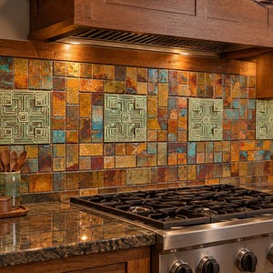 May include: A kitchen backsplash featuring a mosaic of rectangular copper and bronze tiles with oxidized blue-green accents. Four square, light green relief tiles with a geometric, layered square pattern are evenly spaced across the wall.