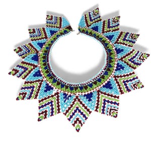 Puede incluir: Un vibrante collar de cuentas con un diseño de sol. El collar muestra una gama de colores, incluyendo turquesa, azul, verde y burdeos. El intrincado trabajo de cuentas forma patrones geométricos, creando una pieza llamativa.