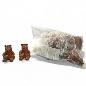 May include: Two brown bear figurines with a fish in their paws are displayed next to a larger brown bear plush toy in a clear plastic bag. The figurines have a glossy finish and are detailed with facial features.