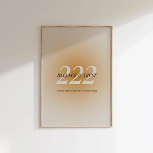 以下が含まれることがあります： ベージュとオレンジのグラデーションの背景に、白い文字で「222 BALANCE & TRUST」と書いてあります。その下に黒い文字で「Cultivate patience and believe in divine timing.」と書いてあります。