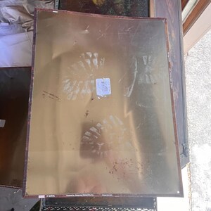 May include: A rectangular metal sign with a gold background and a brown border. The sign has visible wear and tear, including scuffs and marks. The bottom left corner has the Marvel logo and the words "Licensed to Desperate Enterprises, Inc."