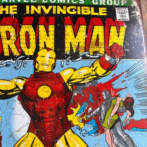 May include: Vintage Iron Man comic book cover featuring the character in a red and gold suit, punching. The cover has the text "MARVEL COMICS GROUP" and "THE INVINCIBLE IRON MAN". The background is blue.