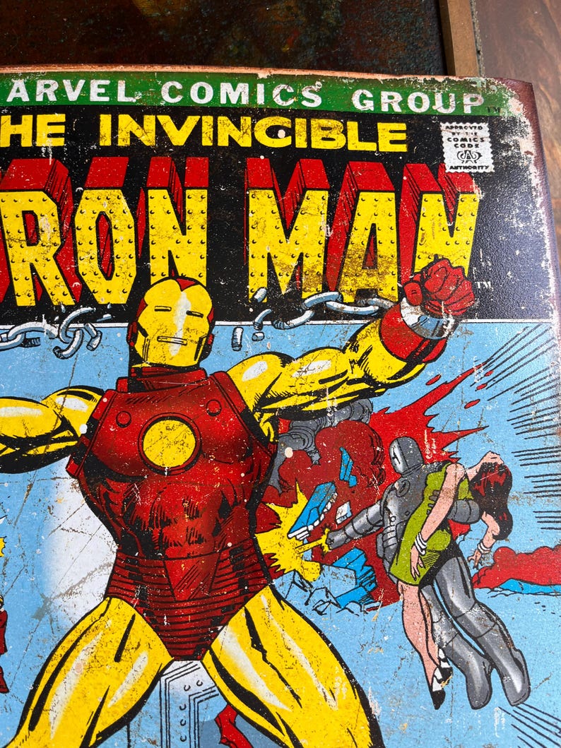 May include: Vintage Iron Man comic book cover featuring the character in a red and gold suit, punching. The cover has the text "MARVEL COMICS GROUP" and "THE INVINCIBLE IRON MAN". The background is blue.