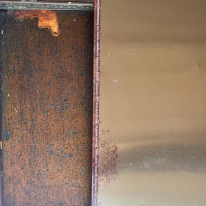 May include: A metal sign with a gold-colored surface and text from Marvel Comics. The sign has some rust and wear. The text includes copyright information and the Marvel website address.