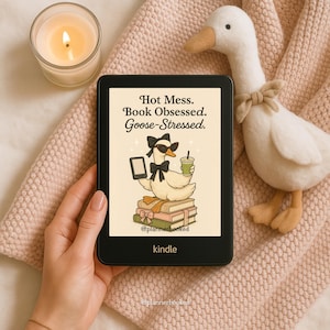 May include: A black Kindle e-reader displaying a cartoon goose with sunglasses, a bow tie, and a drink, atop books. Text reads "Hot Mess. Book Obsessed. Goose-Stressed." A plush goose and lit candle are nearby.