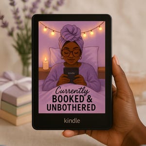 May include: A black Kindle e-reader showing an illustration of a person in bed, holding a Kindle. The image has the text "Currently Booked & Unbothered" and the Kindle logo. The e-reader is held in a hand.