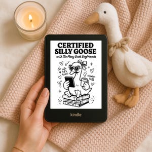 May include: A black Kindle e-reader displays a cartoon goose with heart-shaped sunglasses and the text "CERTIFIED SILLY GOOSE with Too Many Book Boyfriends." A plush goose and lit candle are next to the e-reader on a pink blanket.