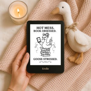 May include: A black Kindle e-reader shows a goose graphic with the text "HOT MESS. BOOK OBSESSED. GOOSE-STRESSED." A plush goose toy and a lit candle are also in the image. The Kindle is held by a person.