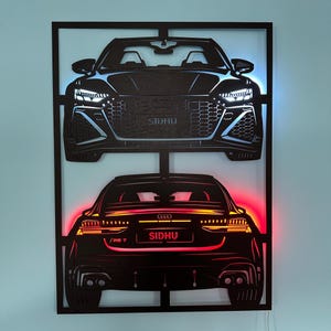 May include: Black metal wall art featuring two car illustrations, one front view and one rear view, with the text "SIDHU" and "/RS 7". The art has blue and red LED lighting.