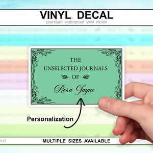 以下が含まれることがあります： 上部に「VINYL DECAL」の文字が入った長方形のビニールデカール。デカールは、装飾的なフレームの中に「THE UNSELECTED JOURNALS OF Rosa Jayne」という言葉が入ったミントグリーンの背景が特徴です。「Personalization」という言葉が下に書かれています。