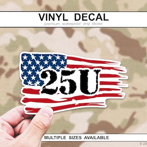 以下が含まれることがあります： 黒い数字「25U」が入った、使い古されたアメリカ国旗のデザインのビニールデカール。デカールは白い縁取りがあり、手で持たれています。「VINYL DECAL」の文字が上部にあります。