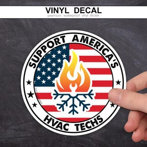 May include: A circular vinyl decal featuring the American flag as a background. In the center, a graphic shows a yellow and orange flame above a dark blue snowflake icon. The text reads SUPPORT AMERICA'S HVAC TECHS in bold black lettering.