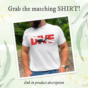 May include: A white short-sleeved t-shirt featuring the word DIVE in bold red and white block letters, with a black silhouette of a scuba diver integrated into the design. The text Grab the matching SHIRT! appears above the image.