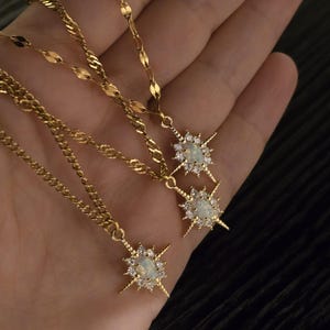 May include: Three gold necklaces with star-shaped pendants featuring opal stones and clear cubic zirconia accents.