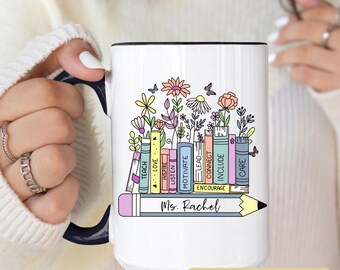 May include: White ceramic mug with a black handle and rim, featuring a colorful floral and book design. The design includes the words "TEACH, LOVE, INSPIRE, LISTEN, MOTIVATE, LEAD, CONNECT, INCLUDE, CARE" and a pencil with the name "Ms. Rachel".